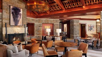 A spacious lobby with a stone fireplace, leather seating, and a wooden ceiling.