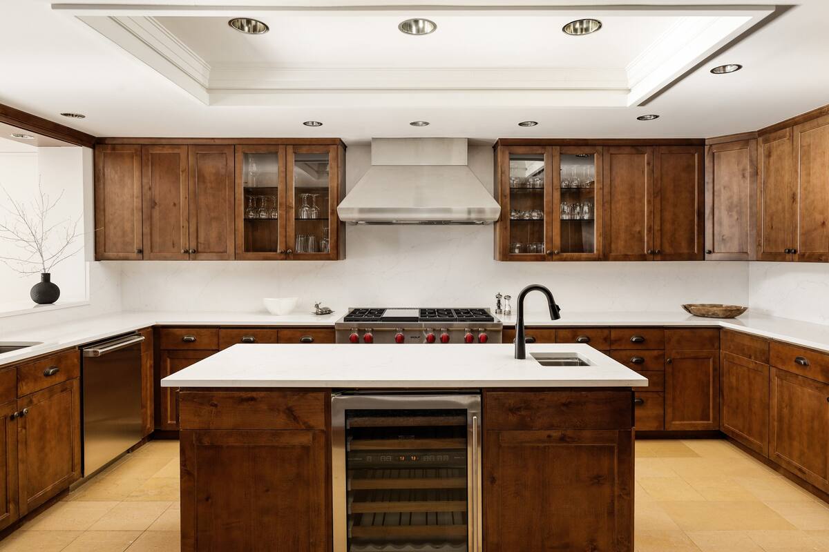 A kitchen with wooden cabinets, a white countertop, a built-in oven, and a dishwasher.