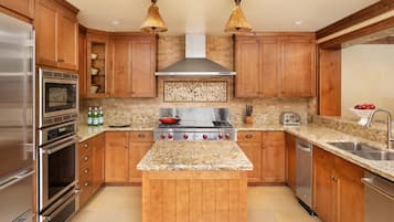 A kitchen with wooden cabinets, a central island, stainless steel appliances, and pendant lighting.