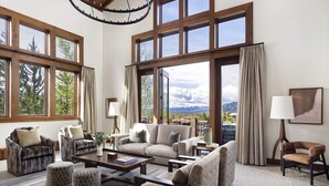 A spacious living room with large windows, a sofa set, a coffee table, and a view of mountains. - Four Seasons Resort Jackson Hole (Teton Village)