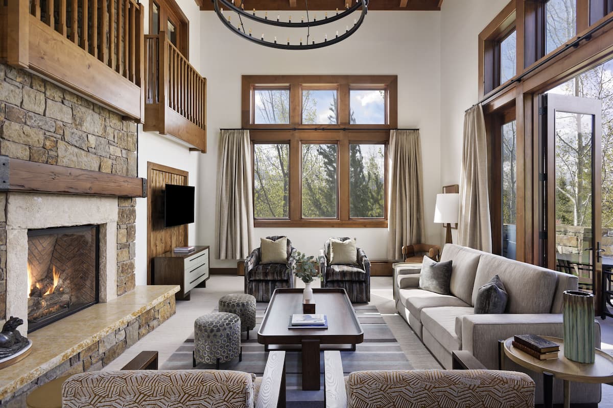 A spacious living room with a stone fireplace, large windows, and a cozy seating area.