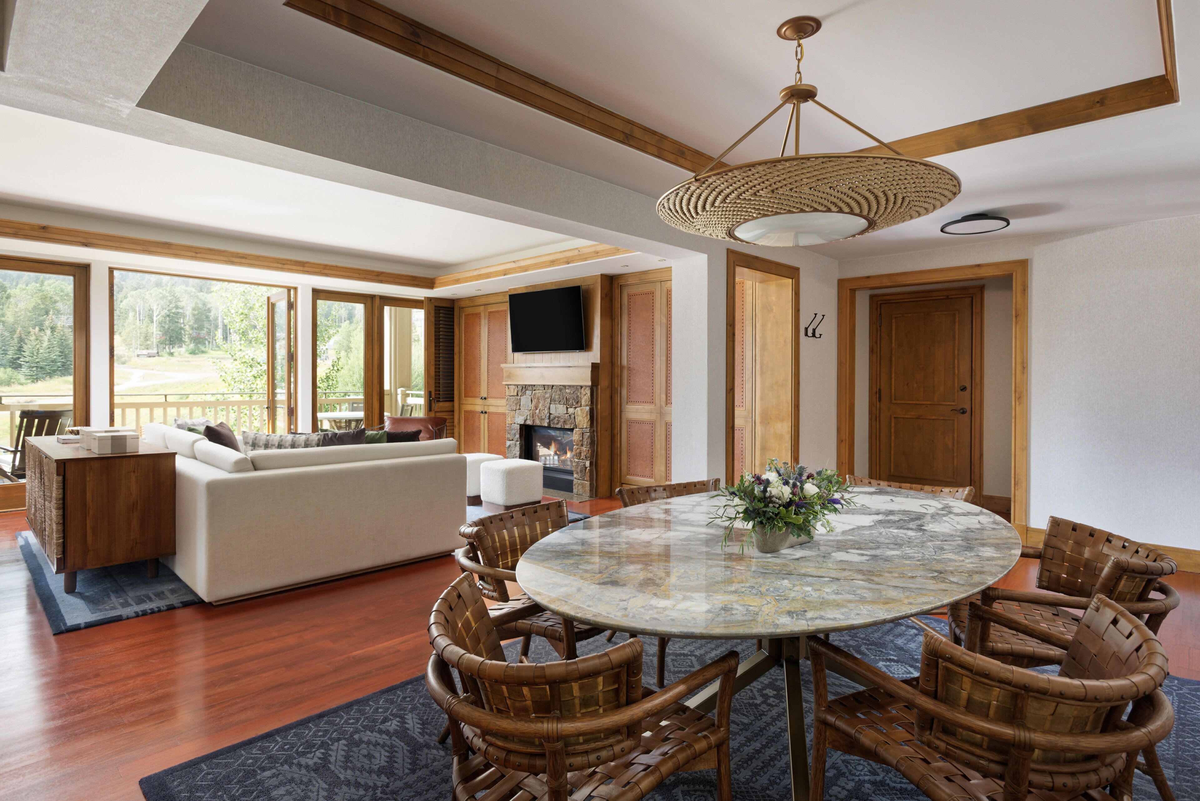 A spacious living room with a large sofa, a dining area with a round table, and a fireplace.