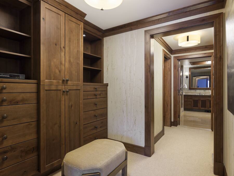 A hallway with wooden cabinets, a bench, and a view into a kitchen area.