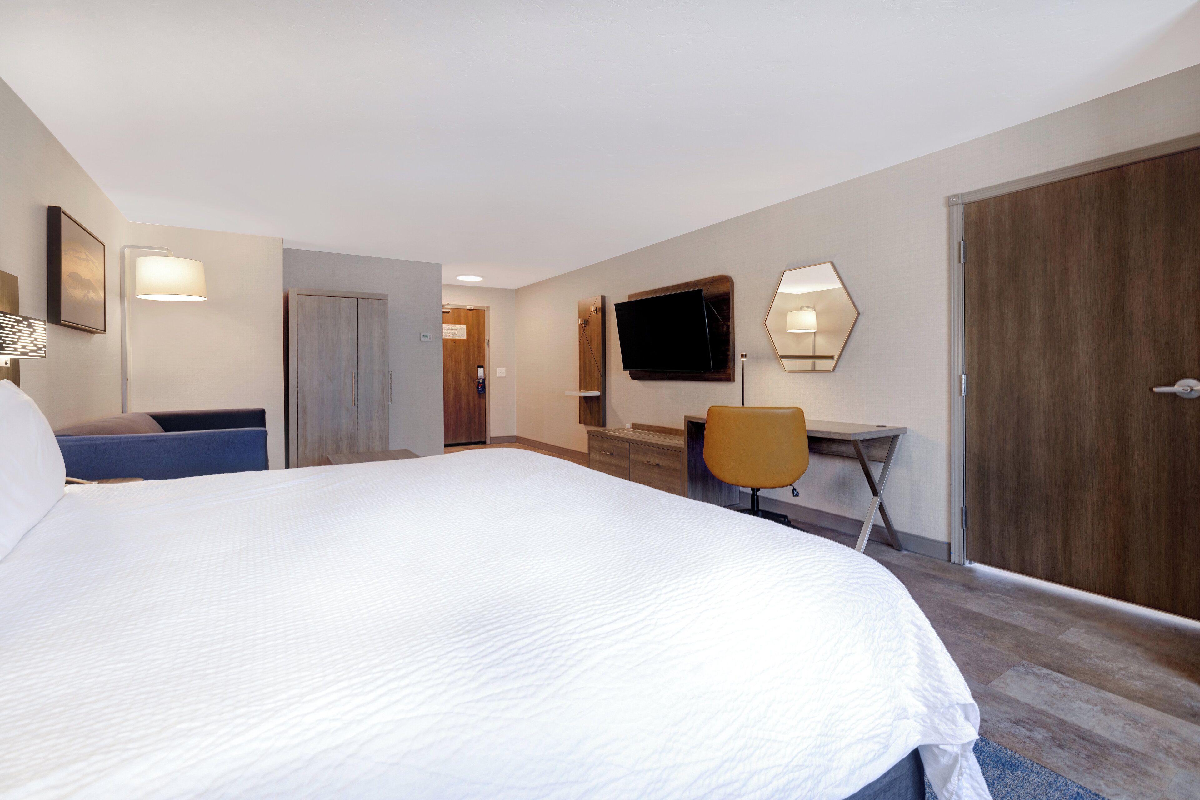 Habitació d'hotel amb un llit gran, una taula de treball, una cadira, una televisió i un armari.