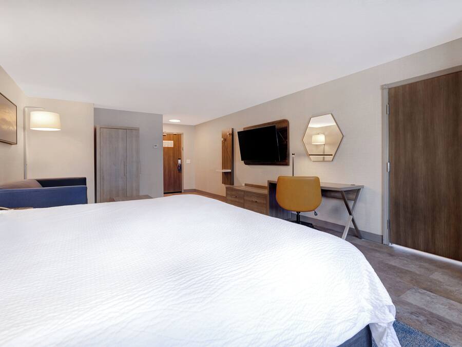 Habitació d'hotel amb un llit gran, una taula de treball, una cadira, una televisió i un armari.