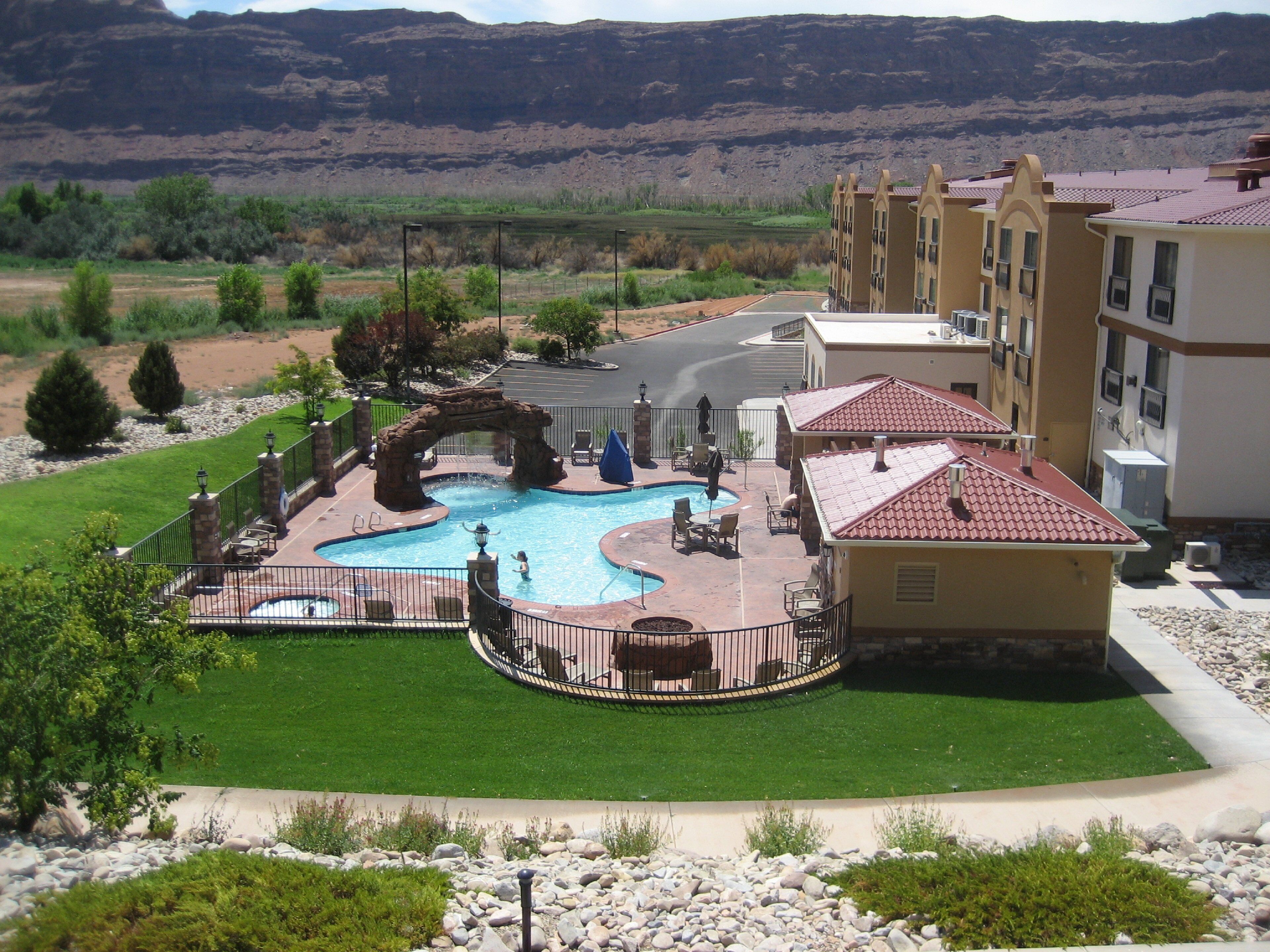 A resort with a swimming pool, outdoor seating, and a view of the mountains.