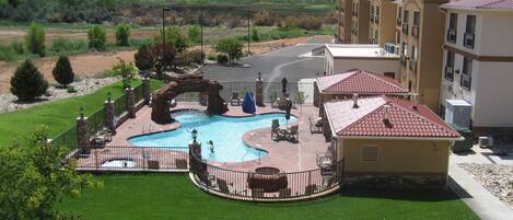 A resort with a swimming pool, outdoor seating, and a view of the mountains.