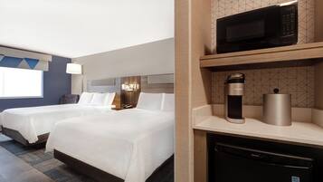 A hotel room with two beds, a microwave, a coffee maker, and a small refrigerator.