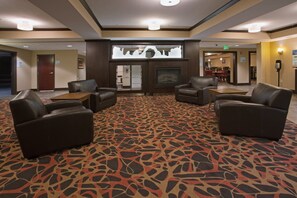 A hotel lobby with leather sofas, a patterned carpet, and a fireplace. - Holiday Inn Express & Suites Moab by IHG (Moab)