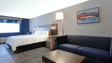 A hotel room with a bed, a sofa, a coffee table, and a painting on the wall.