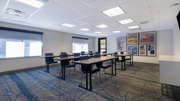 A conference room with a long table, chairs, and a carpeted floor.