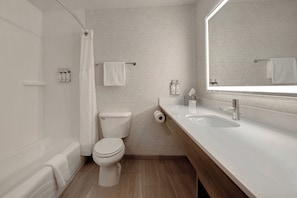 A modern bathroom with a toilet, shower, and sink.