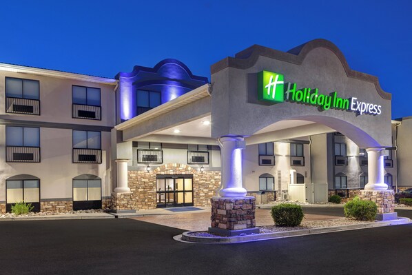 Un edificio de Holiday Inn Express con fachada de piedra, varios balcones y una entrada bien iluminada.