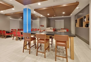 A modern conference room with a long table, red chairs, and a blue accent wall.