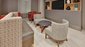 A modern living room with a sofa, chairs, a round table, and a TV mounted on the wall. - Holiday Inn Express Hotel & Suites Dallas - Duncanville by IHG (Duncanville)