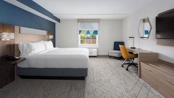 A hotel room with a large bed, a desk, a chair, a TV, and a window with a view.