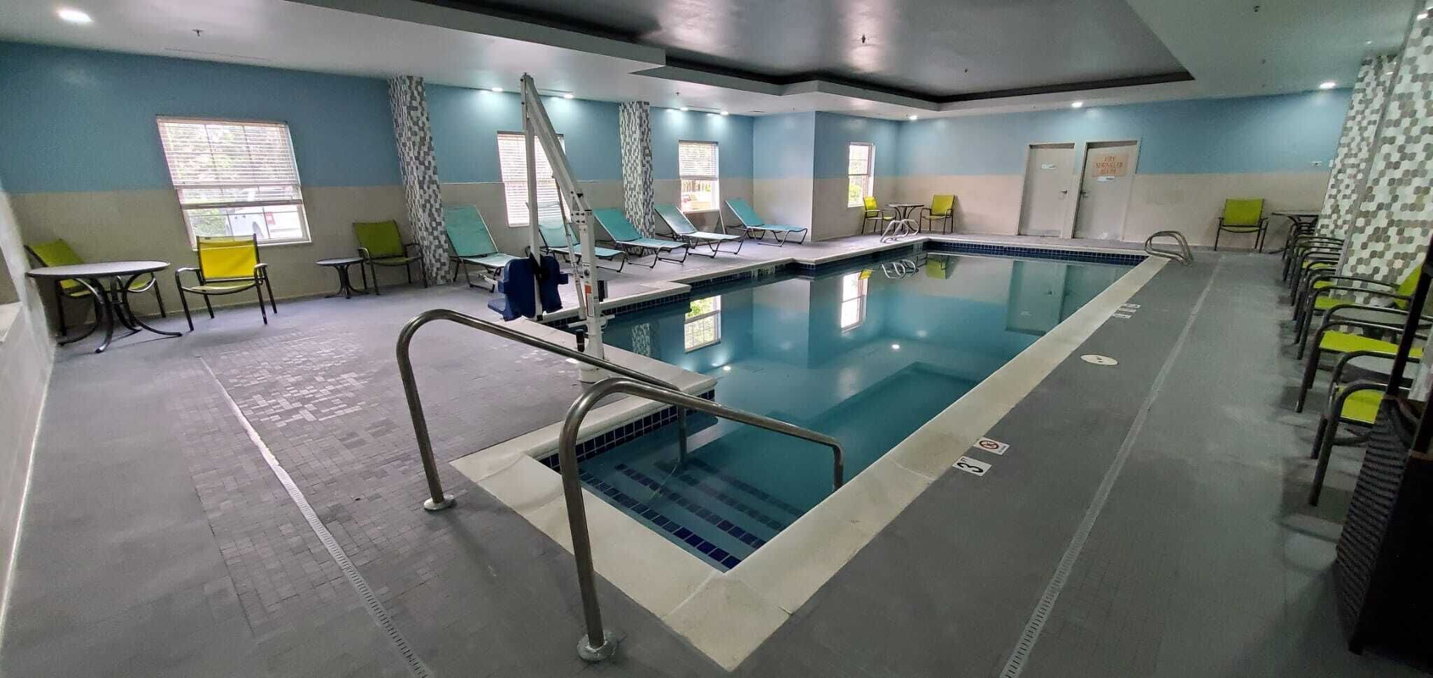A swimming pool with a diving board, lounge chairs, and a changing room.