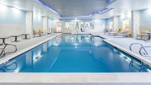 Un'ampia piscina coperta con diverse corsie, poltroncine a sdraio e tavoli lungo i bordi.