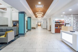A hotel lobby with a reception desk, seating area, and a coffee shop. - Holiday Inn Express & Suites Williamsburg by IHG (Williamsburg)