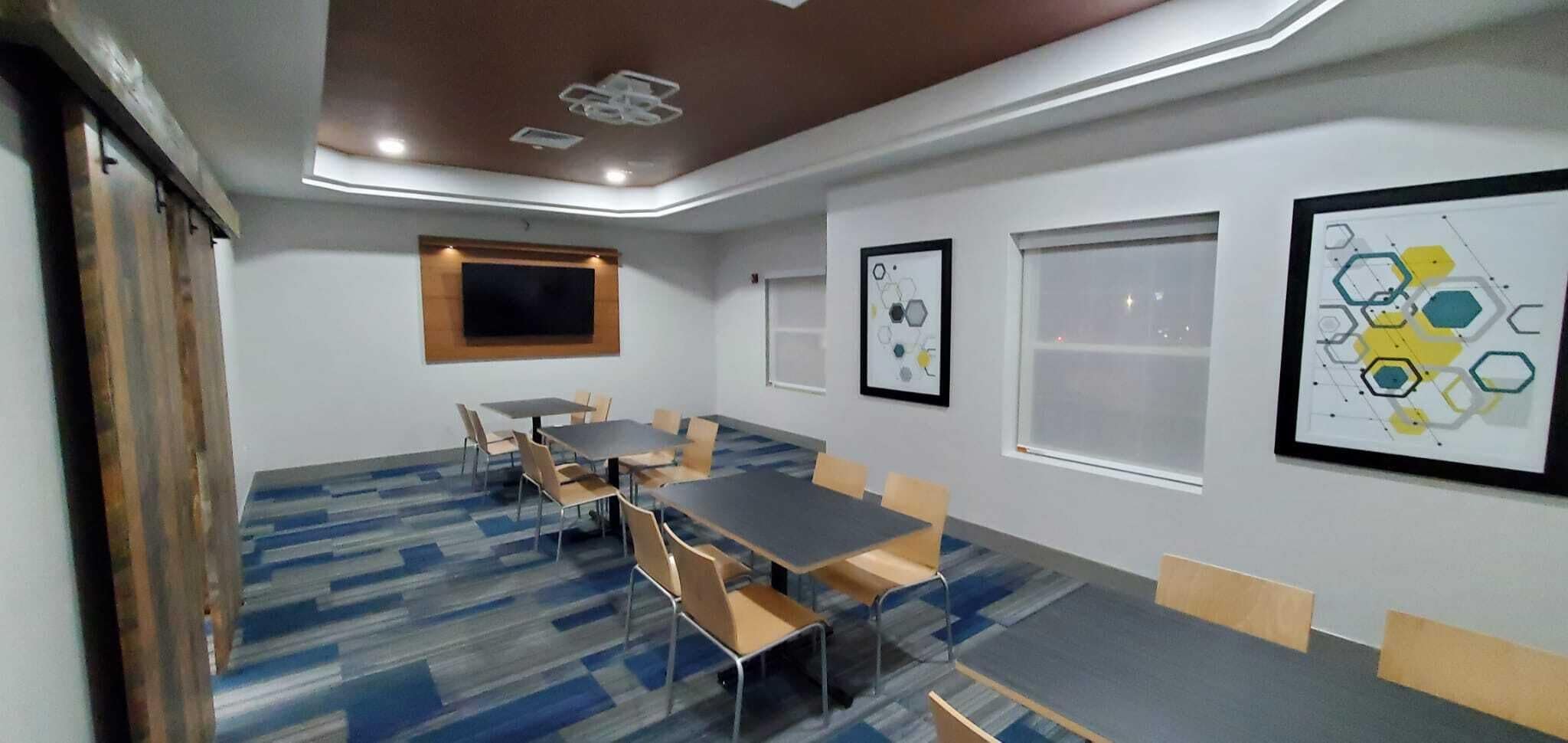 A conference room with a large table, chairs, a ceiling light, and framed artwork on the walls.
