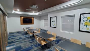 A conference room with a large table, chairs, a ceiling light, and framed artwork on the walls.