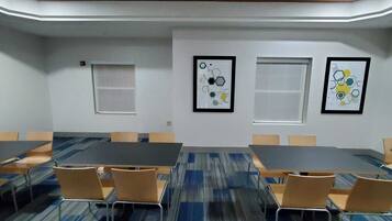 A conference room with a long table, chairs, and framed abstract art on the walls.