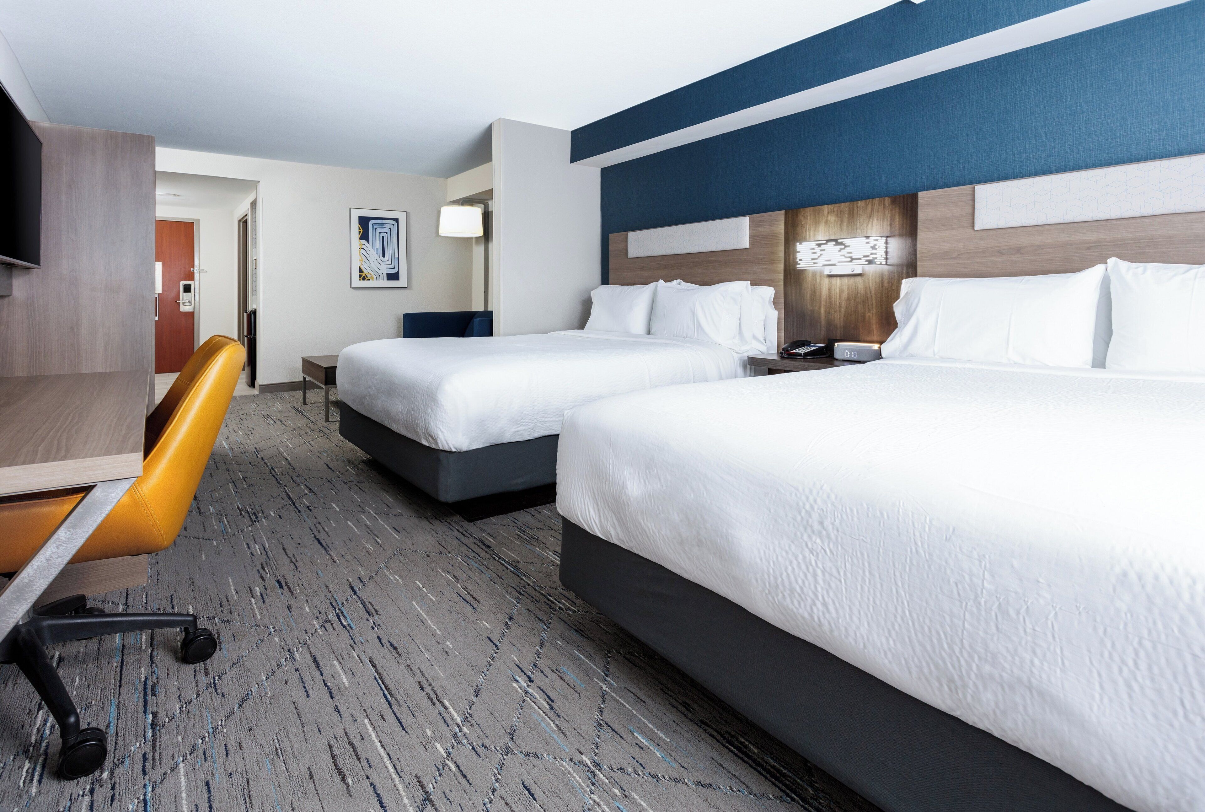 Une chambre d’hôtel avec deux lits, un bureau et une chaise.