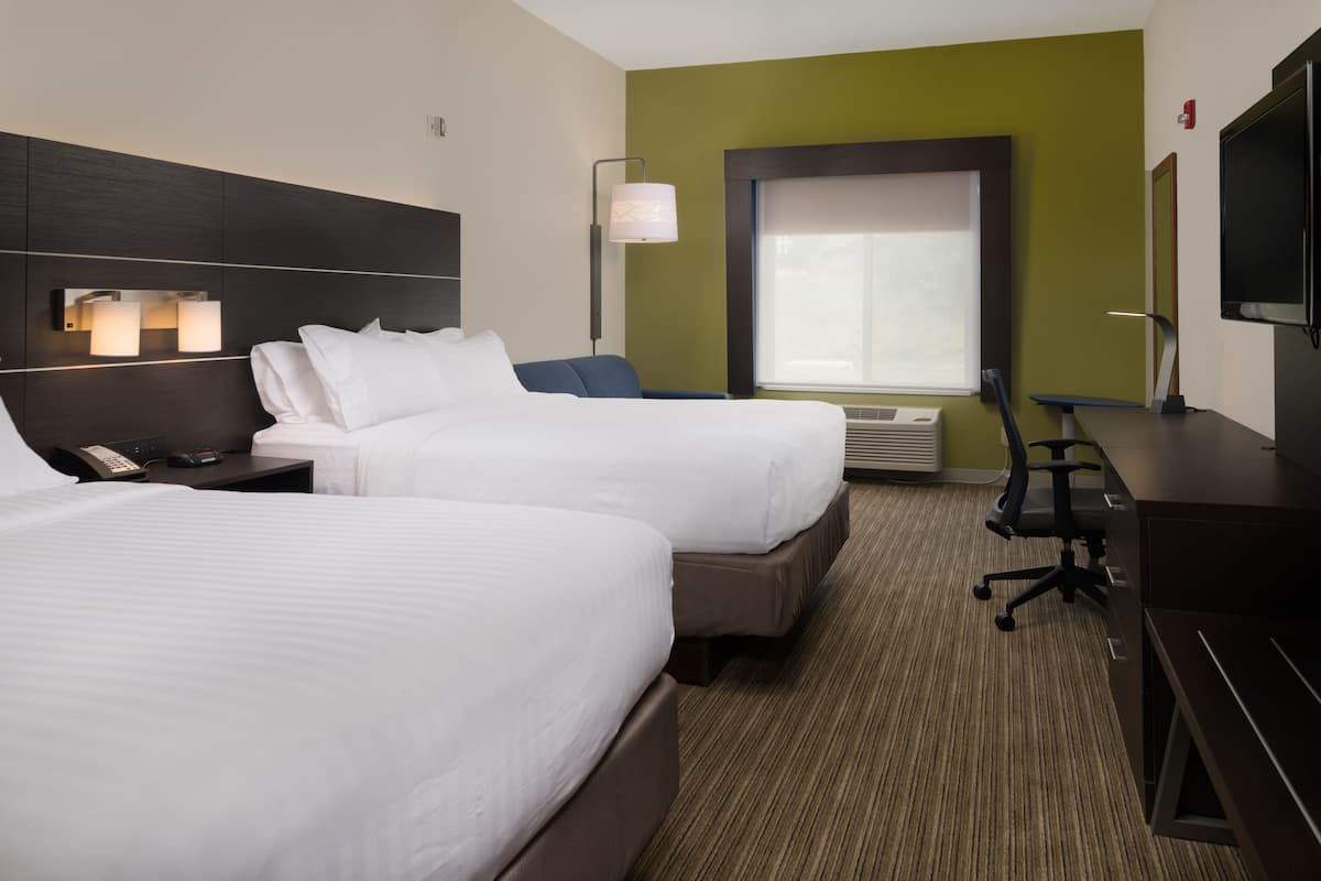 A hotel room with two beds, a desk, a chair, a TV, and a window with blinds.