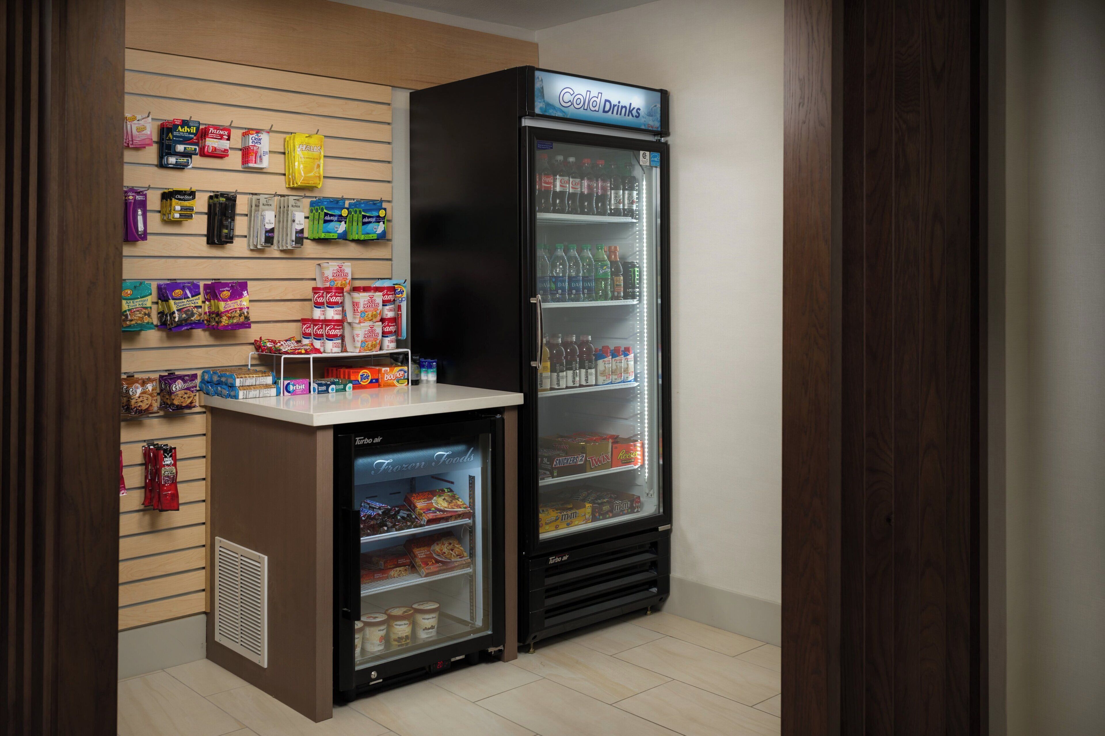 Una pequeña tienda de conveniencia con sección refrigerada para bebidas frías y alimentos congelados.