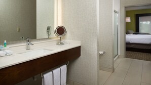 A hotel bathroom with a double sink, a mirror, and a glass shower enclosure. - Holiday Inn Express Hotel & Suites Independence-Kansas City by IHG (Independence)