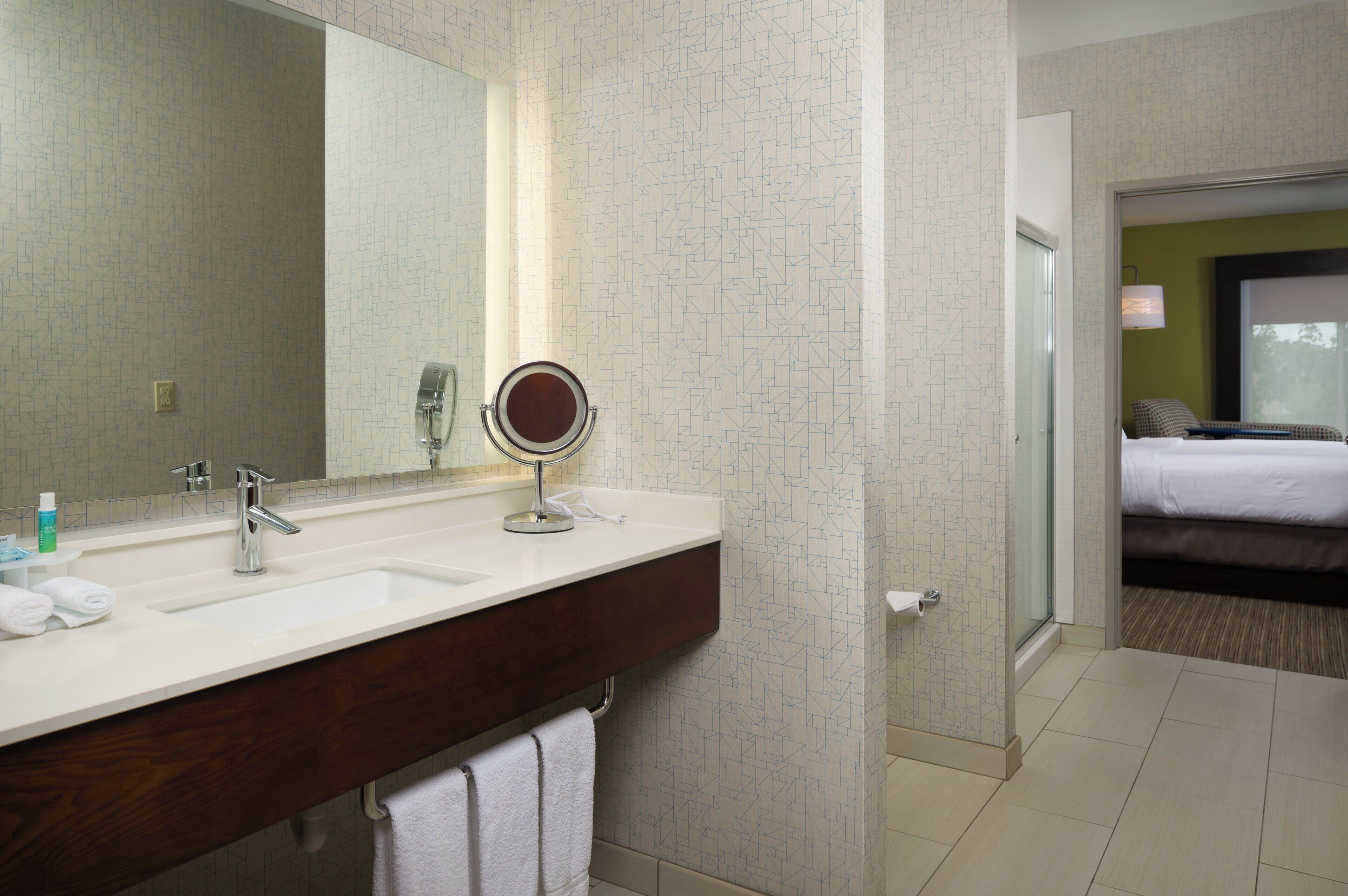 Une salle de bain d’hôtel avec un double lavabo, un miroir et un porte-serviettes.