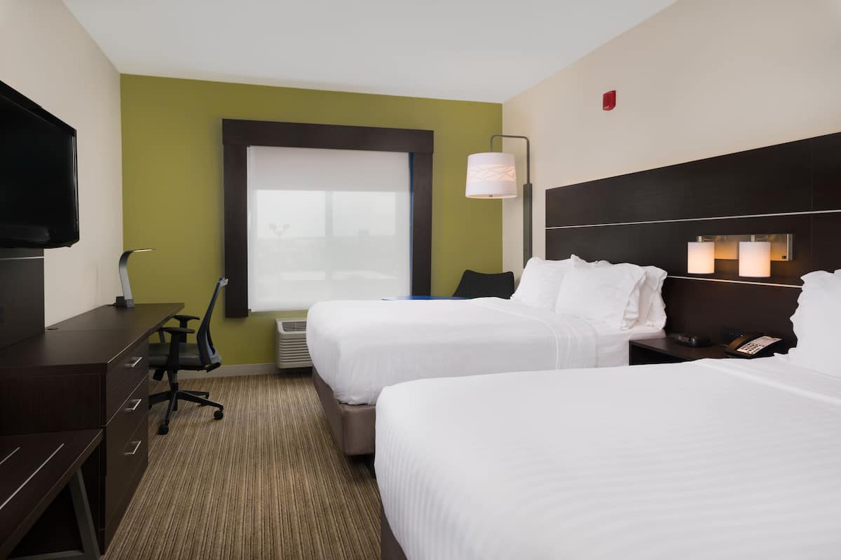 A hotel room with two beds, a desk, a chair, a TV, and a window with a view.