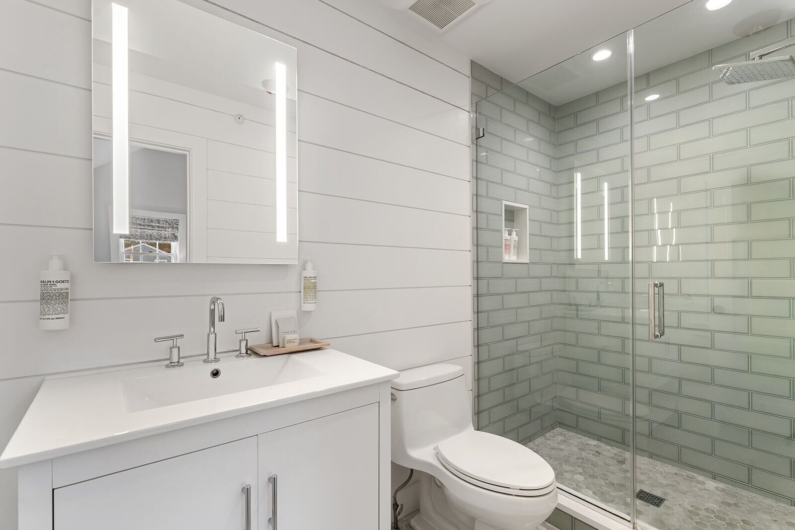 Une salle de bain moderne avec un meuble-lavabo blanc, une douche en verre et des toilettes.