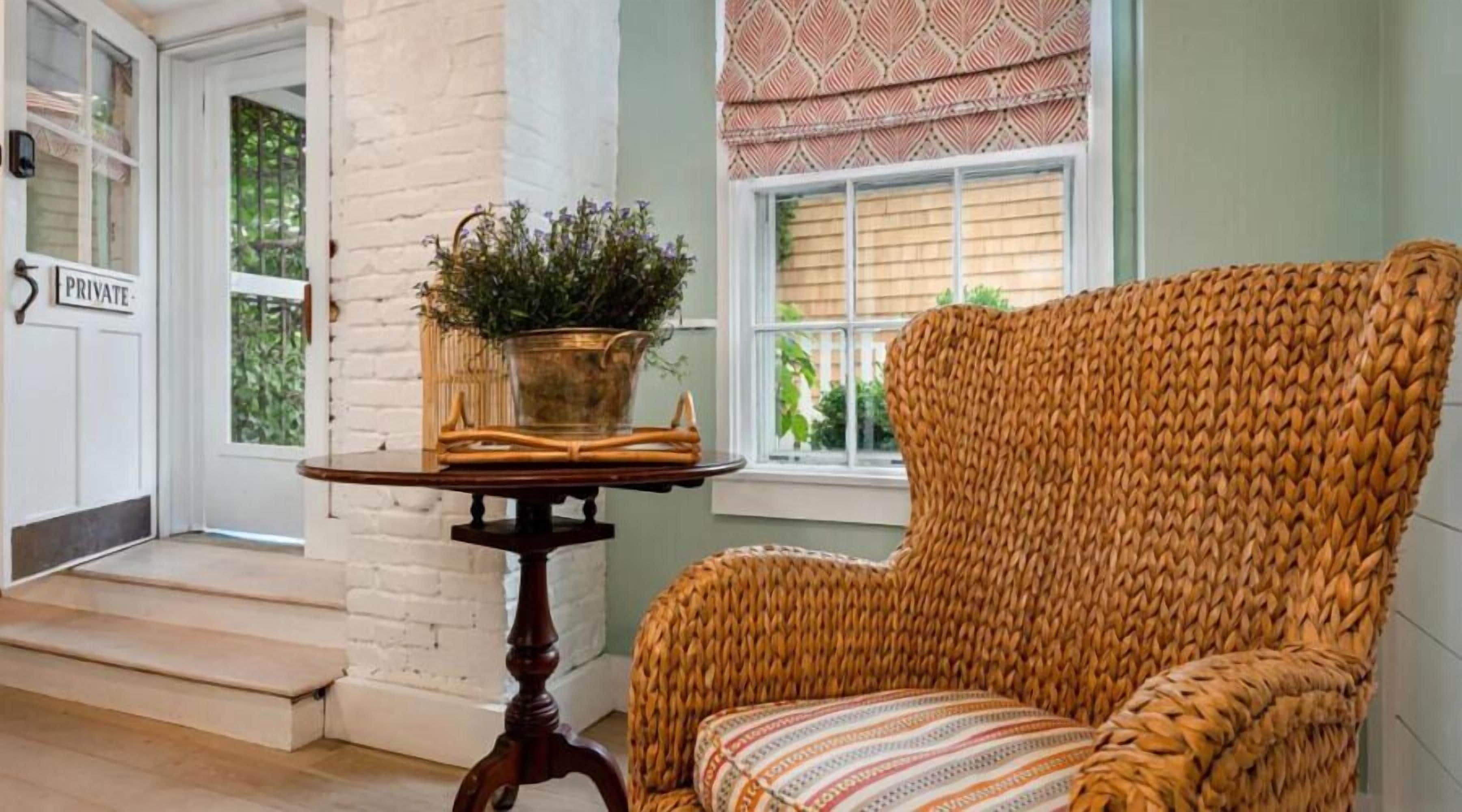 A wicker chair with a patterned cushion, a small table with a potted plant, and a 'PRIVATE' sign on a door.