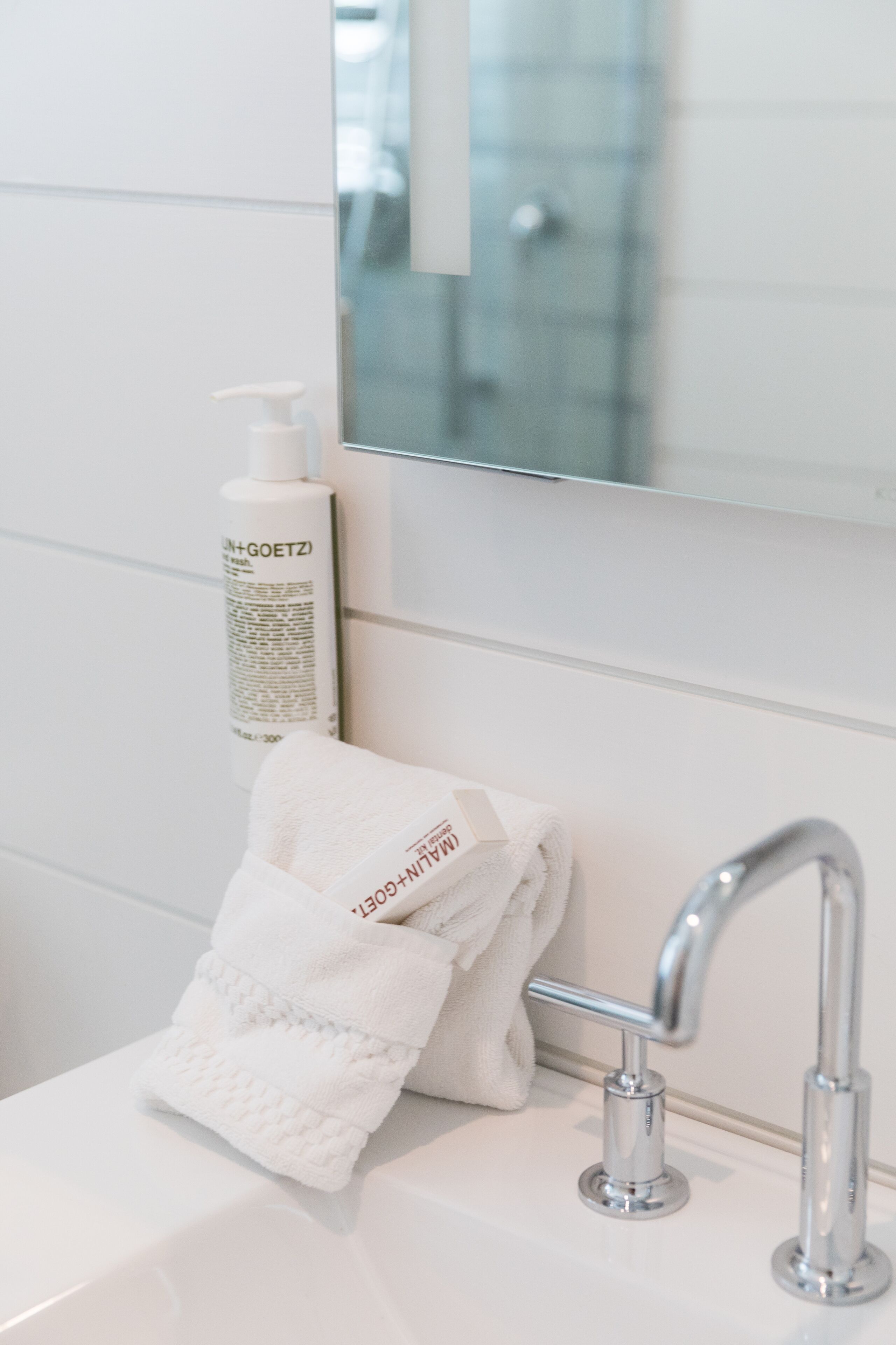 A bathroom with a white sink, a towel, and a bottle of shampoo.