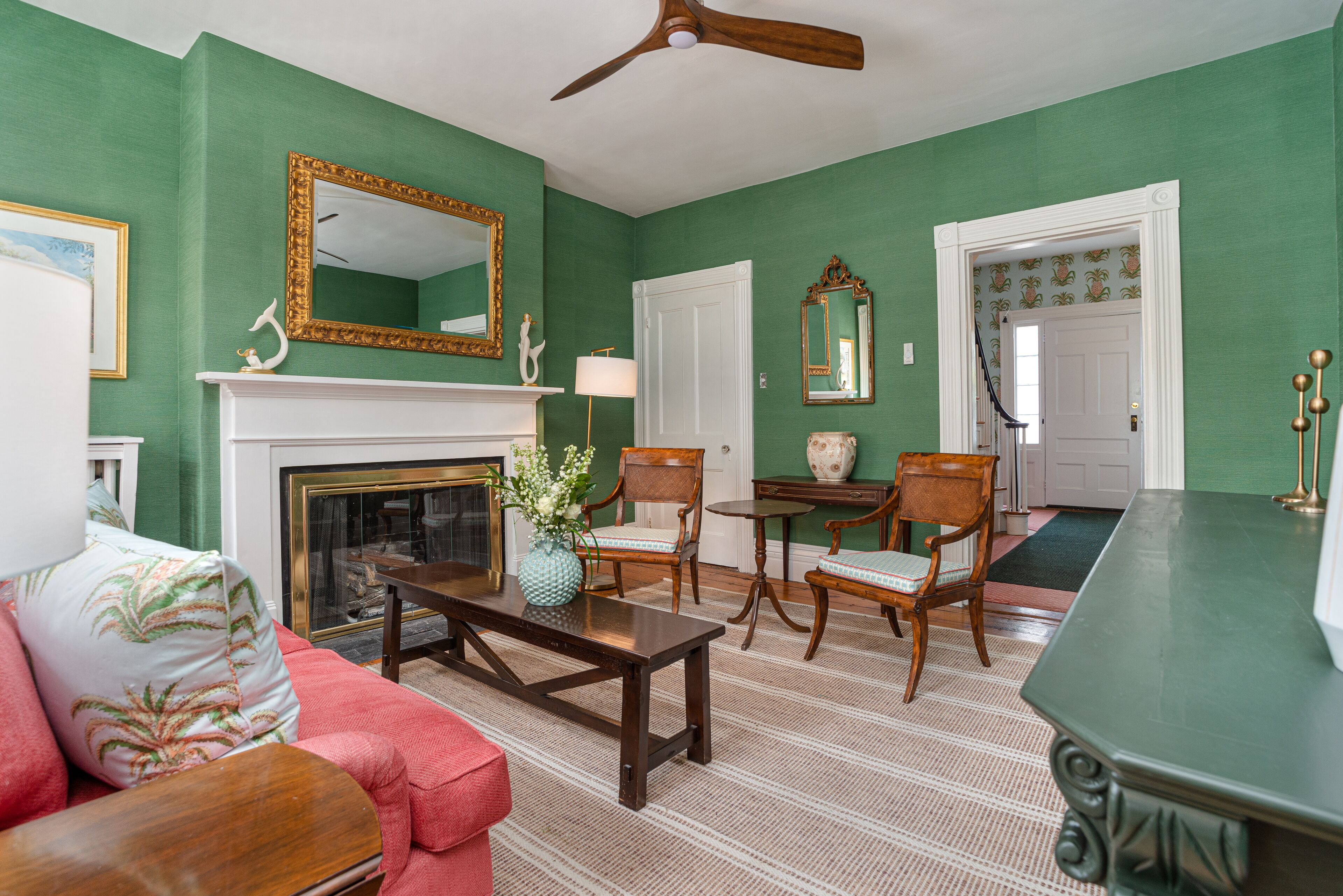 A living room with a fireplace, green walls, and a ceiling fan.