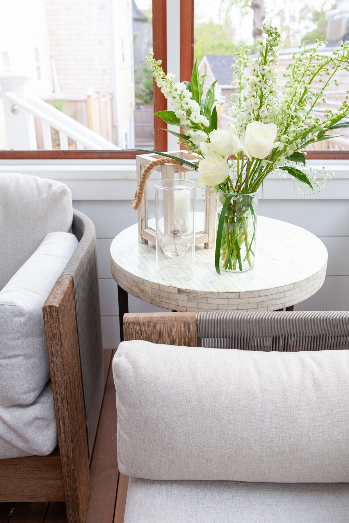 A cozy seating area with a round table, a vase with flowers, and a lantern.