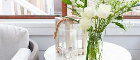A cozy seating area with a round table, a vase with flowers, and a lantern.