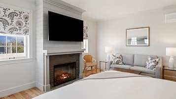 A modern bedroom with a fireplace, a television, a sofa, and a bed.