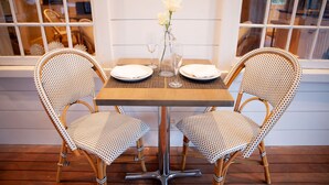 A dining table with two wicker chairs, a vase with white flowers, and two plates with napkins. - Nantucket Resort Collection (Nantucket)