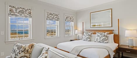Una habitación de hotel con una cama grande, un sofá y tres ventanas con cortinas estampadas.