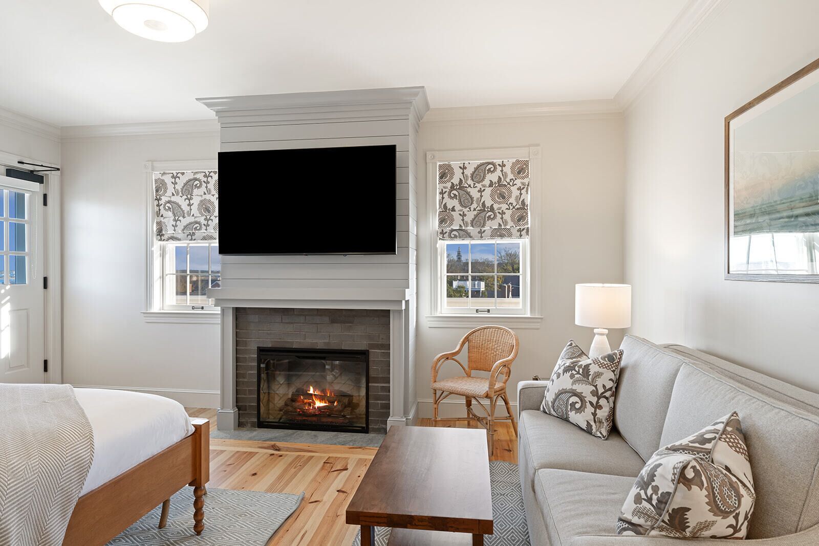A modern living room with a fireplace, a flat-screen TV, a sofa, a chair, and a table.