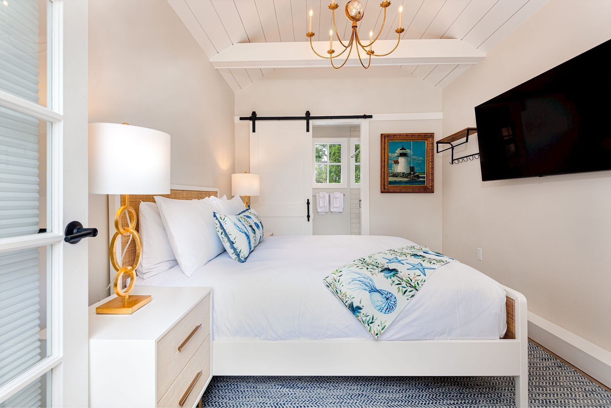 A bedroom with a bed, bedside table, lamp, and a painting on the wall.