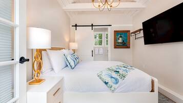 A bedroom with a bed, bedside table, lamp, and a painting on the wall.