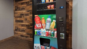 Een automaat met diverse dranken en snacks, een duwdeur en een digitaal beeldscherm.
