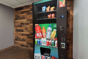 Máquina expendedora con diversas bebidas y aperitivos, una puerta automática y una pantalla digital.