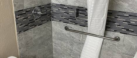 Un baño con ducha, inodoro y pared de azulejos con diseño de ladrillo.