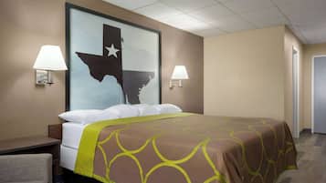 A hotel room with a large bed, two bedside lamps, a nightstand, and a wall-mounted map of Texas.
