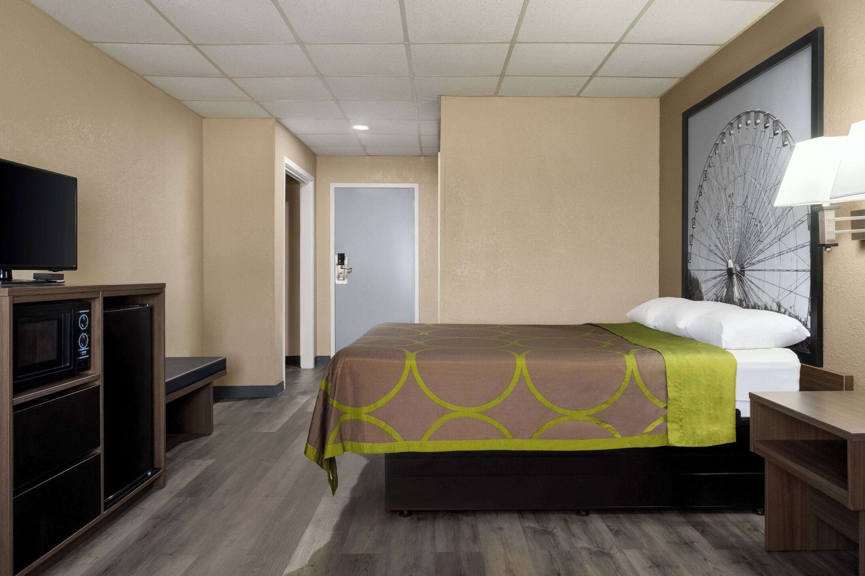Una habitación de hotel con una cama, televisión, escritorio y un adorno grande en la pared.