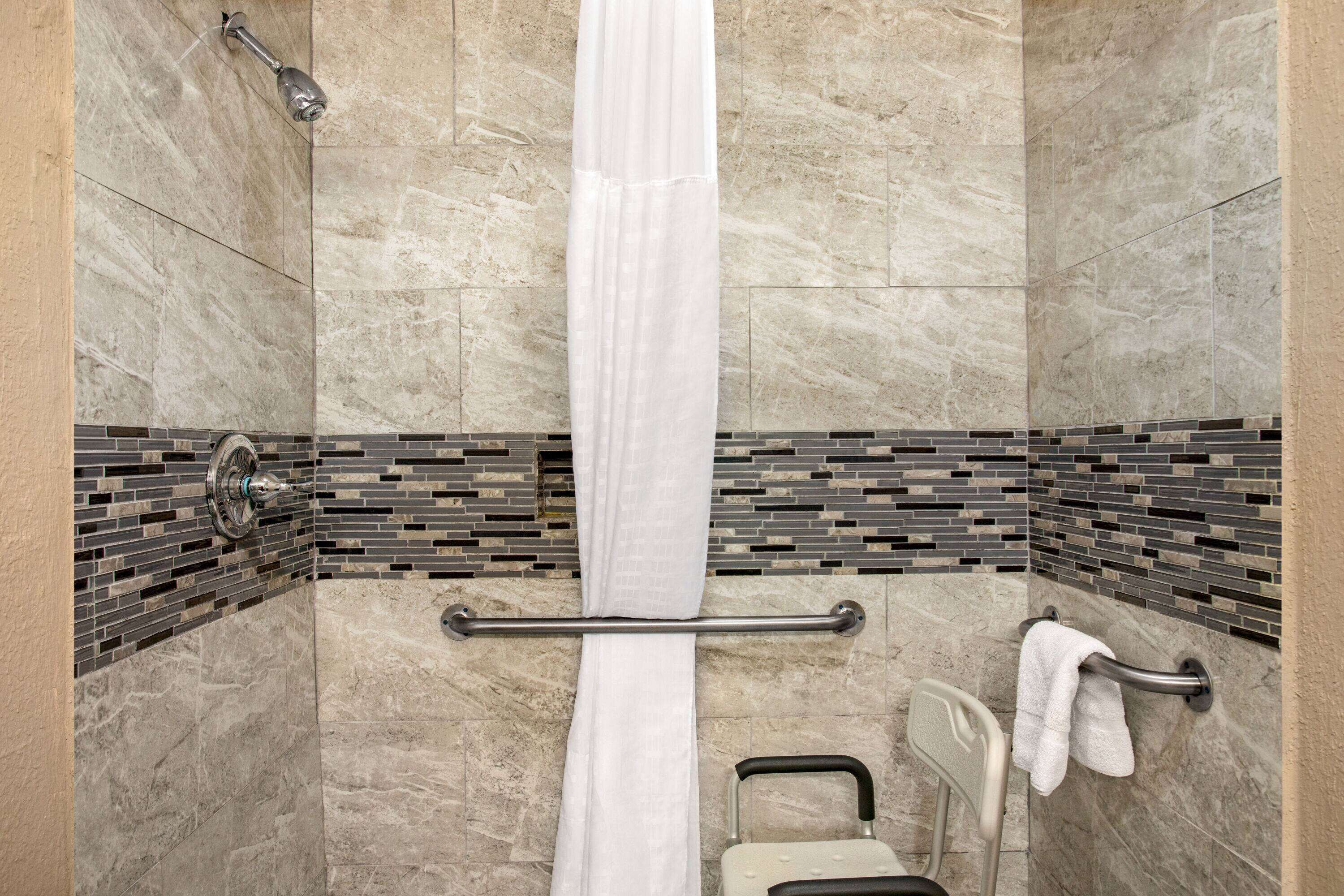 A shower with a glass door, a glass shower head, and a towel rack.